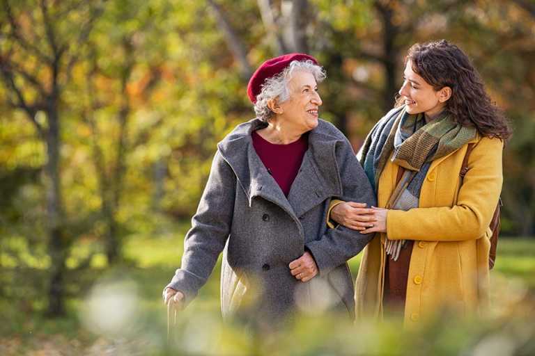 Eine ältere Frau spaziert mit einer jüngeren Frau in der Natur.