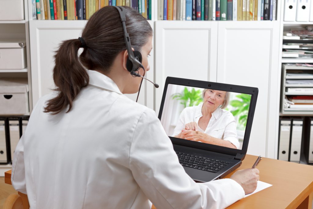 telemedicine concept, older woman with laptop during an online consultation with her doctor in her living room