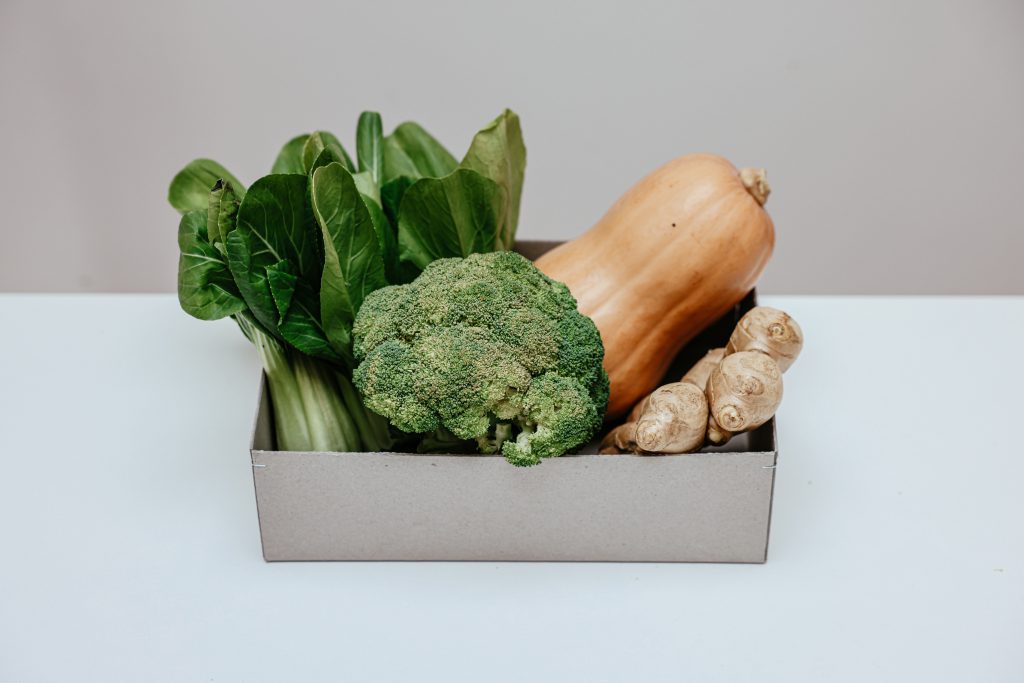 Auf dem Bild ist eine Kiste mit Gemüsen zu sehen, darunter Brokkoli, Kürbis, Ingwer, usw.