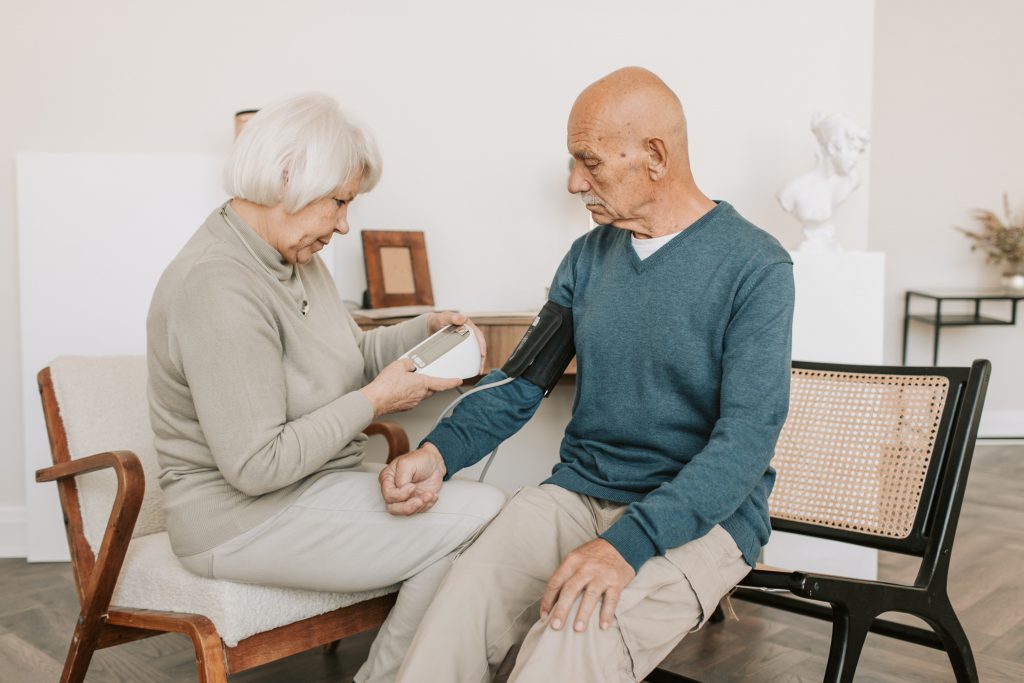 Eine ältere Frau misst den Blutdruck ihres Ehemannes.