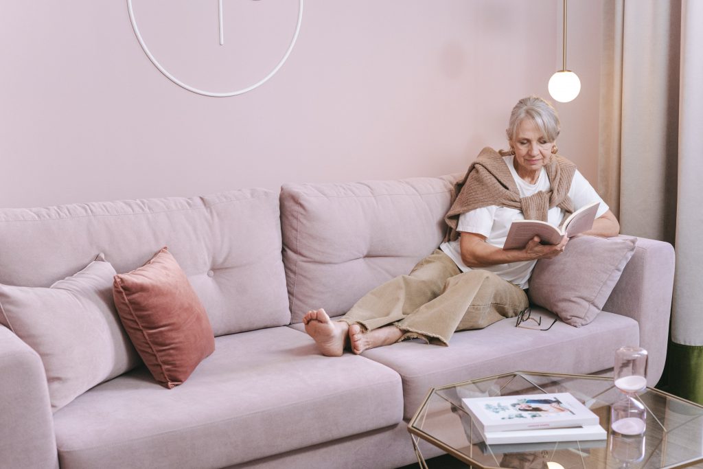 Auf dem Bild sitzt eine ältere Frau auf ihrem Sofa